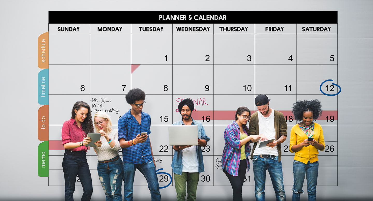 A group of students standing in front of a large wall calendar