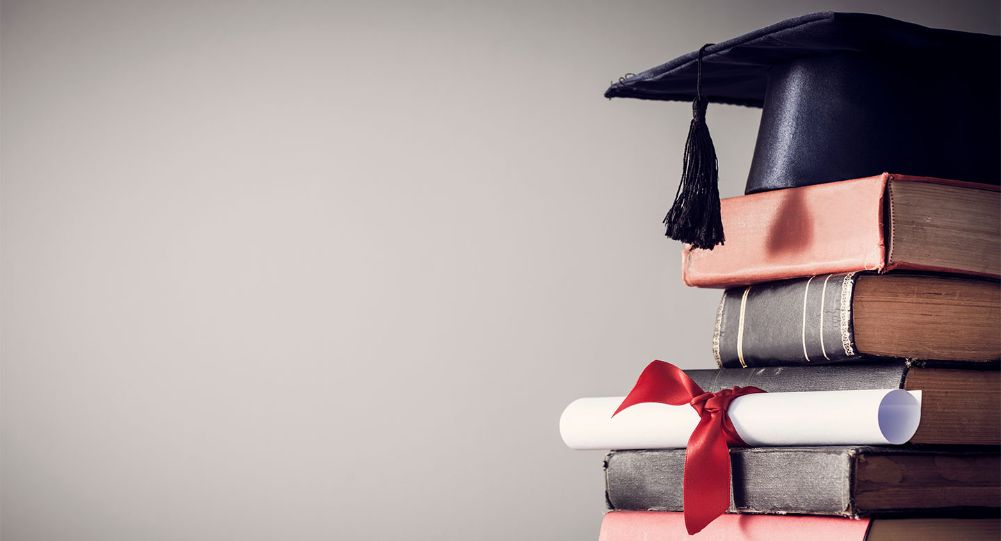 A graduation cap and diploma on a stack of books