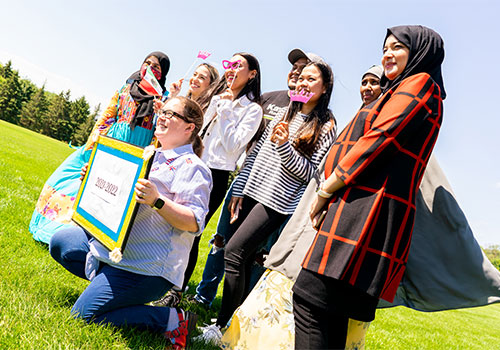 A group of students and faculty outside, posing for a picture. Some wear the hijab or khimar