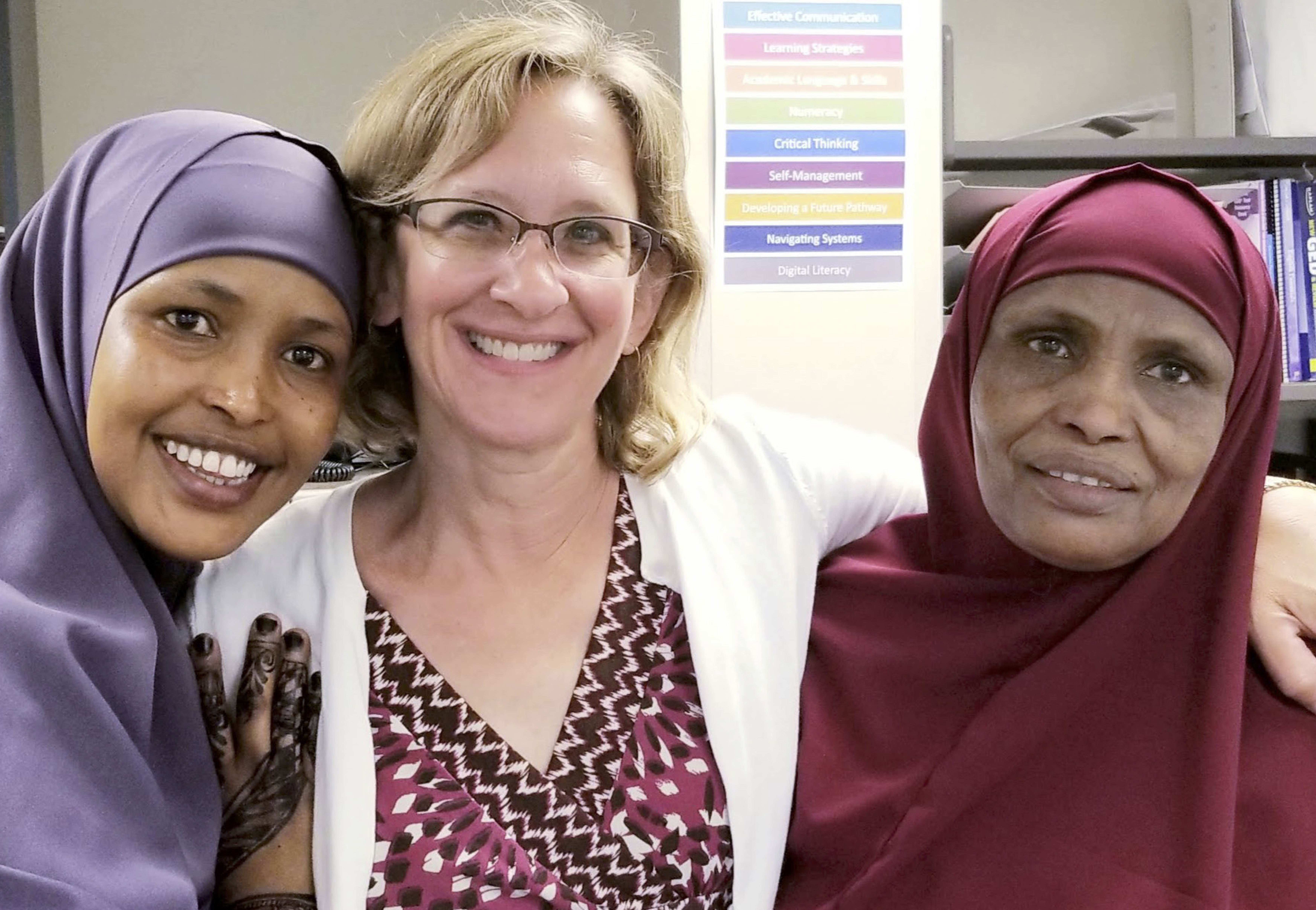 A group of students and faculty outside, posing for a picture. Some wear the hijab or khimar