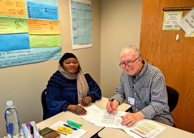 Older male volunteer working with female student on social studies